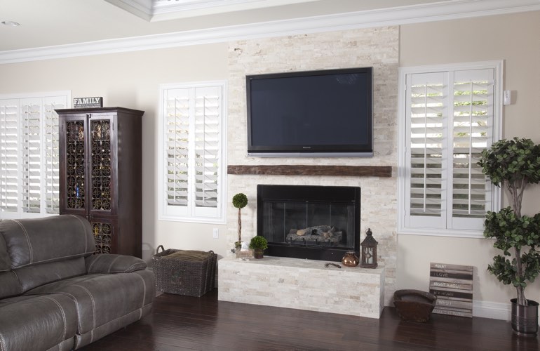White plantation shutters in a Gainesville living room with dark hardwood floors.